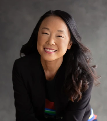 Portrait of Joan Kang Shin on a gray background.