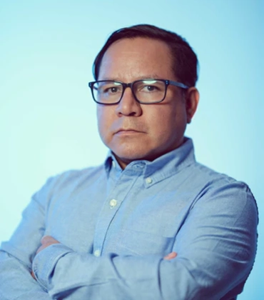 Portrait of Yecid Ortega on a light blue background.